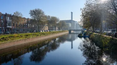 Foto van het Haagse Verversingskanaal tussen de Conradkade en Suezkade met uitzicht op de energiecentrale in het Regentessekwartier