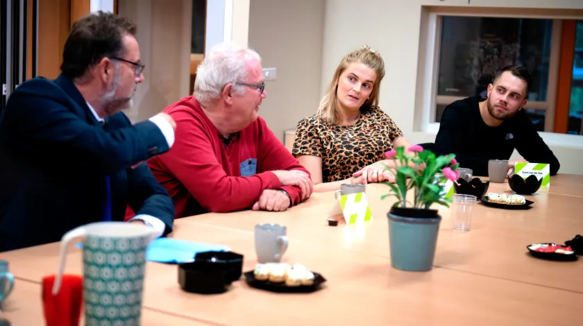 Vier mensen overleggen aan een tafel