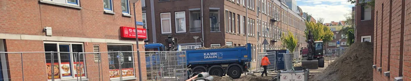 Opengebroken straat met zwarte leidingen voor aansluiting op het warmtenet