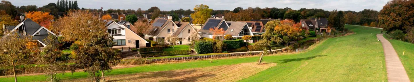 Wandelpad in het groen langs de Zwolse woonwijk Berkum, met vrijstaande woningen met puntdaken voorzien van zonnepanelen.