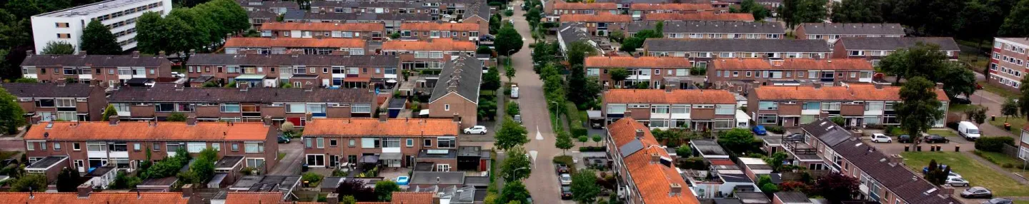 Luchtfoto van rijtjeshuizen met rode daken uit de jaren 60 in de Assense wijk de Lariks