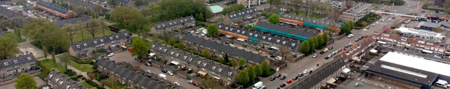 Luchtfoto van een woonwijk met typische jaren '60-rijwoningen en op de voorgrond utiliteitsbouw